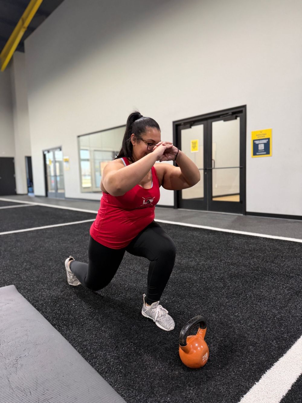 Client in a Level Above Fitness tank doing a lunge on the turf