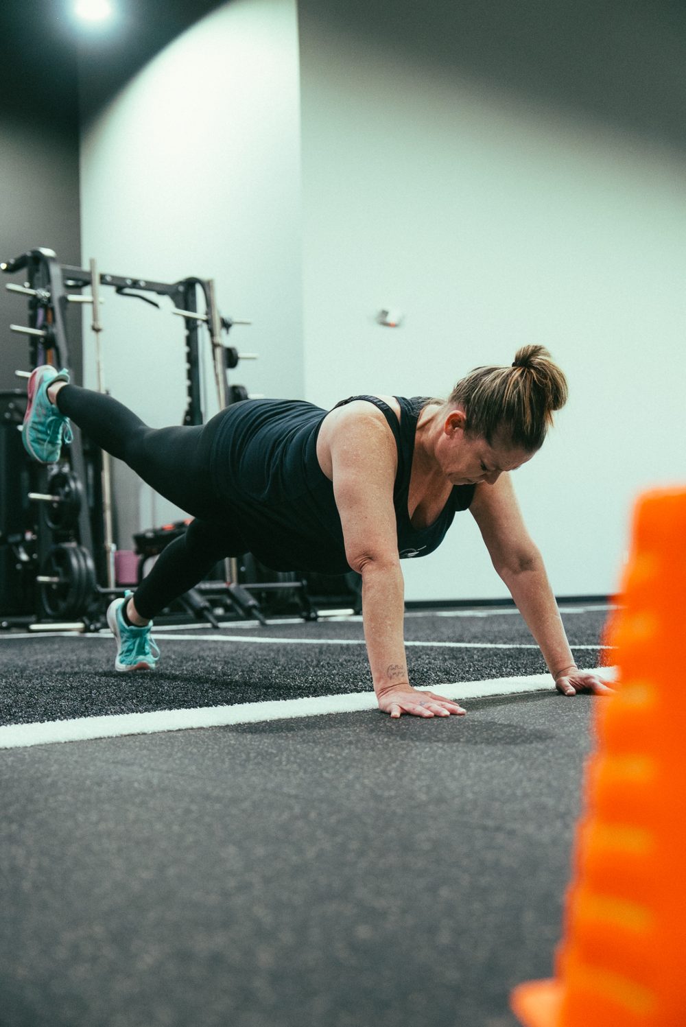 Client doing a plank with one leg raised on the turf at Level Above Fitness