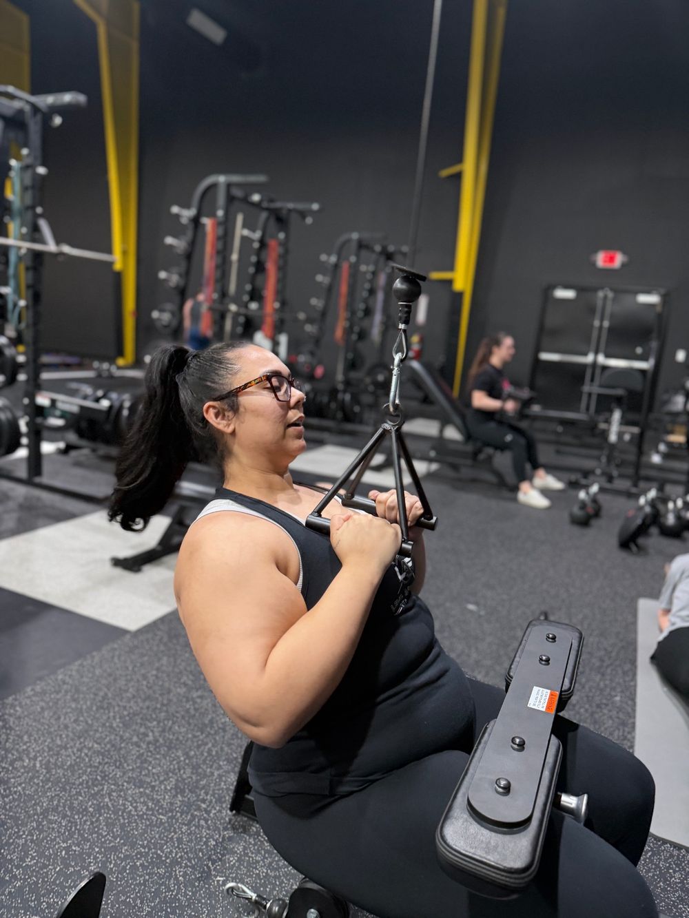 Client doing a seated row with other clients training in the background