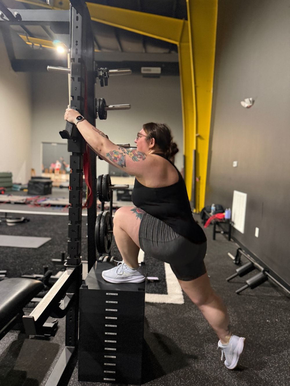 Client stretching at a squat rack in the Level Above Fitness gym